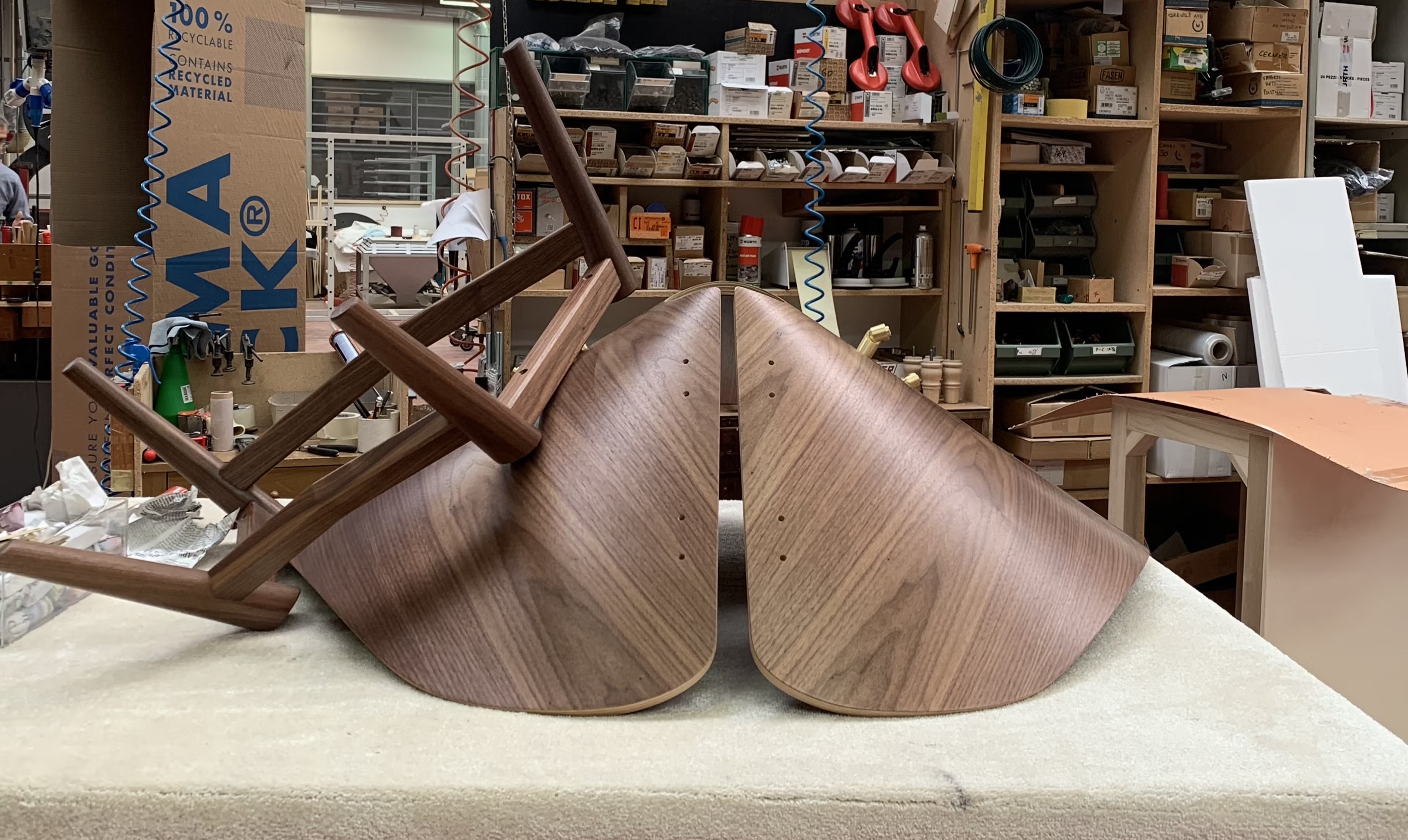 Handcrafted in Brianza: curved walnut shells and solid-wood legs in the workshop before assembly.